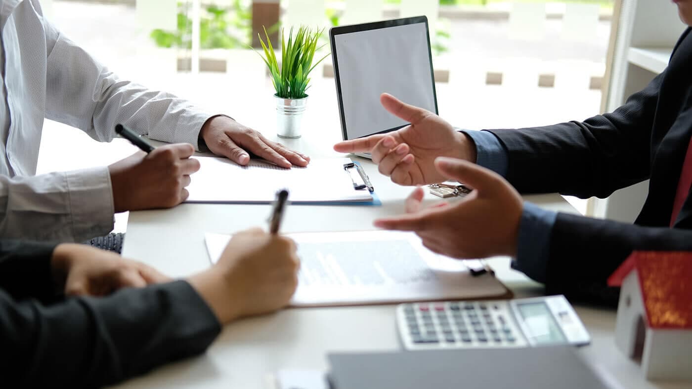 Client signing property documents across a desk from an adviser